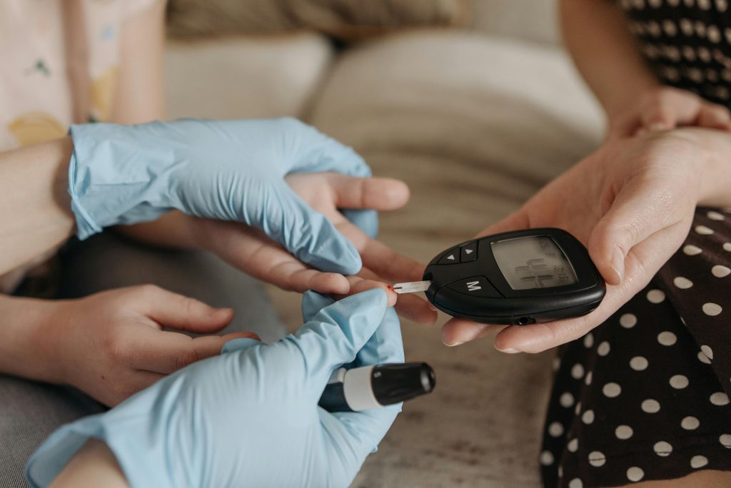 pexels-photo-7653134-7653134 Hands measuring blood glucose levels with a glucose meter and test strip.